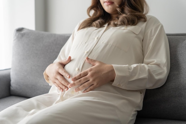妊娠中の女性は腹に手を握り赤ちゃんに触れ彼女の健康を心配しています美しい幸せな妊娠中の 女性 x妊娠中の気分写真 xA