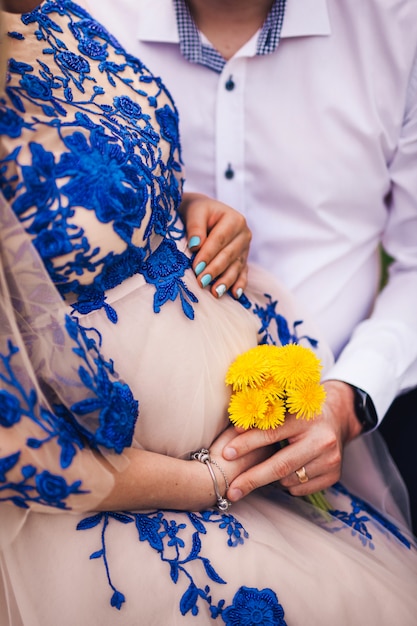 写真 妊娠中の女性は彼女の手で春の花を保持します