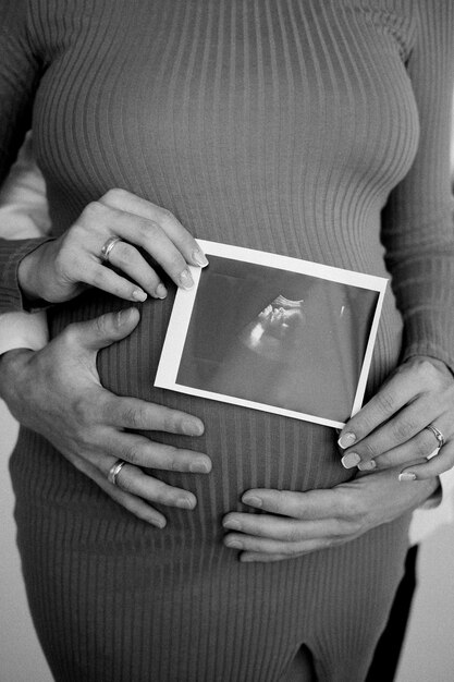 Photo a pregnant woman holds an ultrasound picture