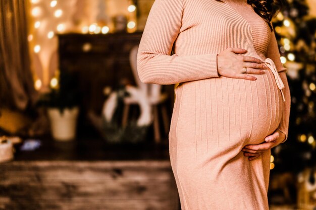 Pregnant woman hugging her belly and posing against the background of christmas decor. Photo