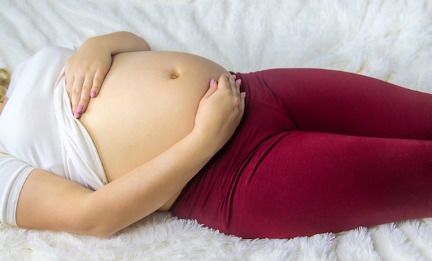 Беременная женщина обнимает ее живот. Выборочный фокус.