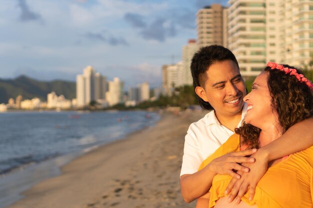 Pregnant woman and husband standing on beach