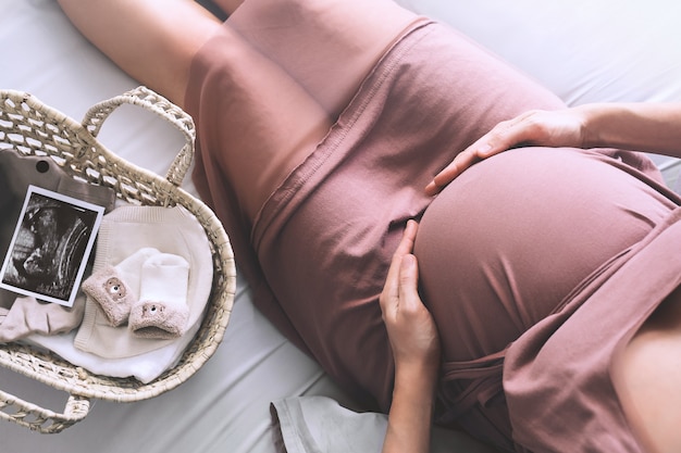 사진 드레스를 입은 임산부는 배에 손을 얹고 임신 중에 아기를 기다리는 임산부