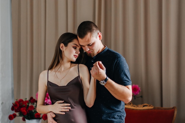 A pregnant woman is dancing with her husband