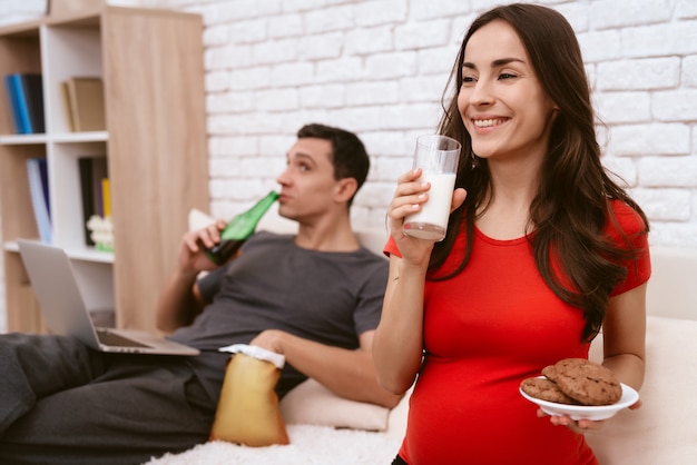 A pregnant woman is drinking milk and smile.