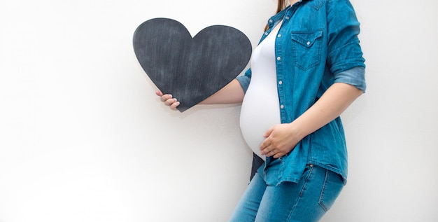 A pregnant woman is holding a blank tablet template for your text.