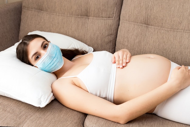 Беременная женщина лежит на диване у себя дома