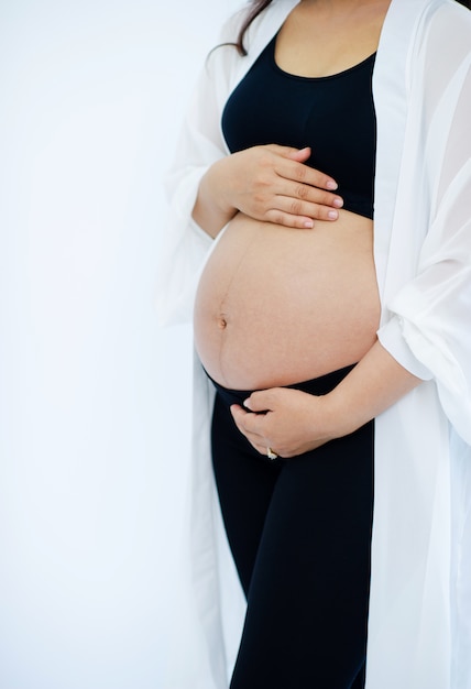 Foto la donna incinta è incinta di una stanza bianca.