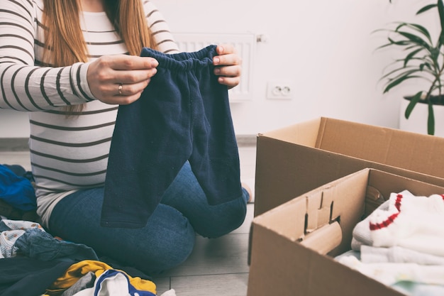 The pregnant woman is sorting baby clothes