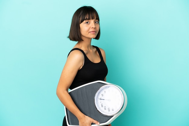 Pregnant woman over isolated background with weighing machine