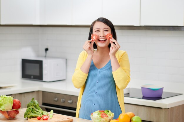 Беременная женщина на кухне готовит овощной салат