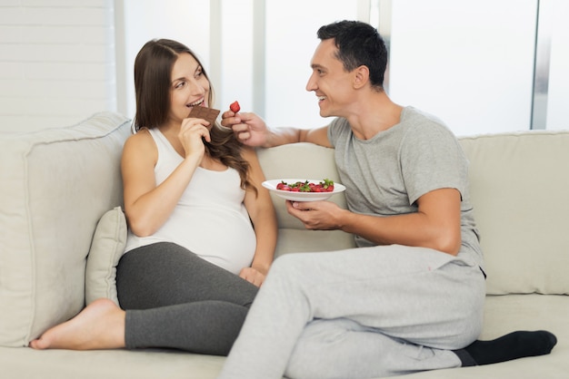 Photo pregnant woman lies on light sofwith man.