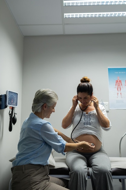 Pregnant woman listening baby heartbeat with stethoscope in hospital