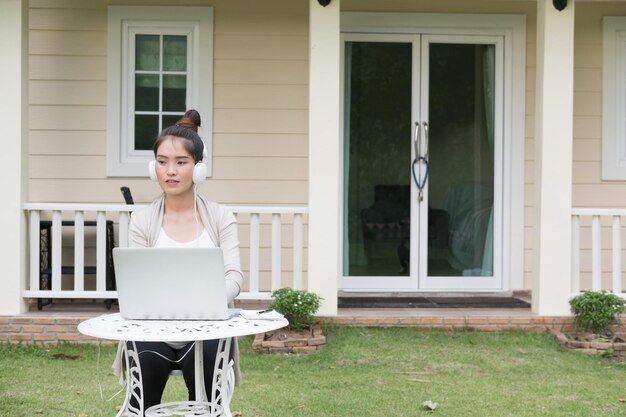 Pregnant woman listening music over laptop while sitting at table on grass