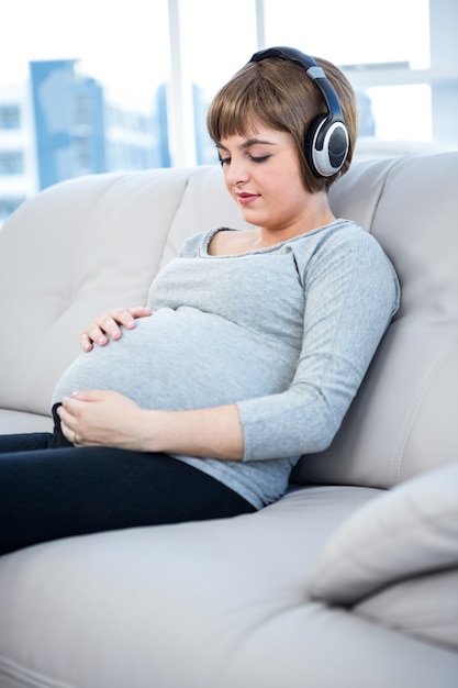 Pregnant woman listening to music while sitting in living room