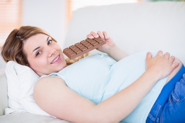 Photo pregnant woman looking at camera and eating chocolate