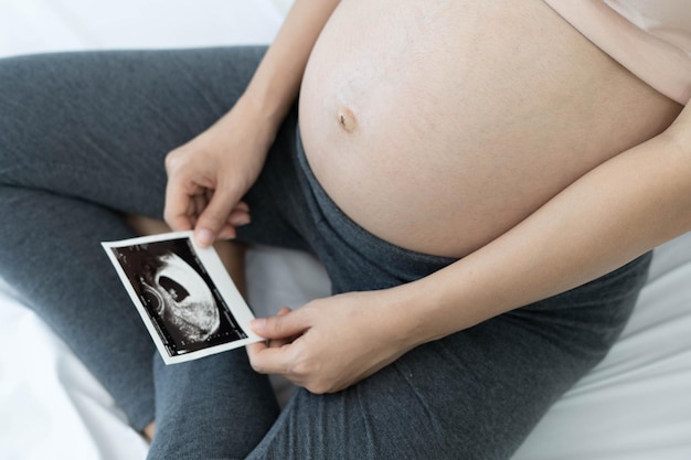 Donna incinta che guarda le foto ecografiche del feto le donne sono alla 28a settimana di gravidanza o nell'ultimo trimestre