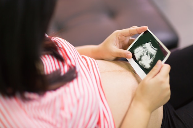 Photo pregnant woman looking at ultrasound scan of baby