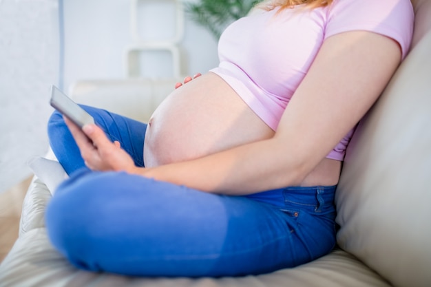 Pregnant woman looking at ultrasound scans and touching her belly