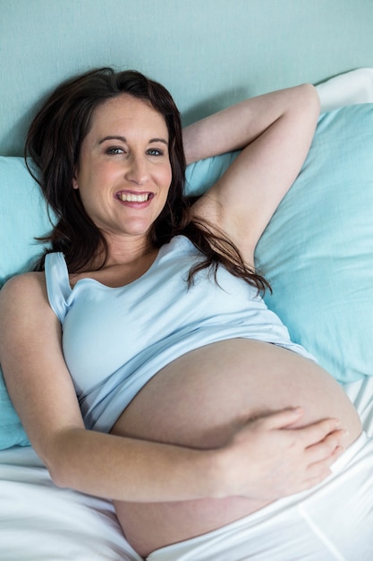 Pregnant woman lying on bed at home 