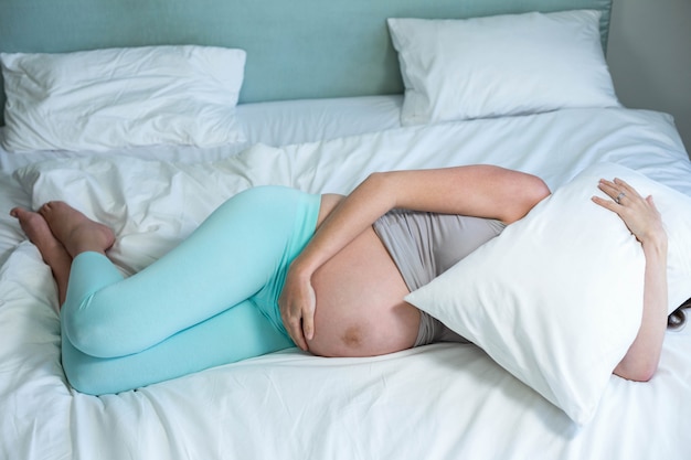 Pregnant woman lying on her bed in her bedroom