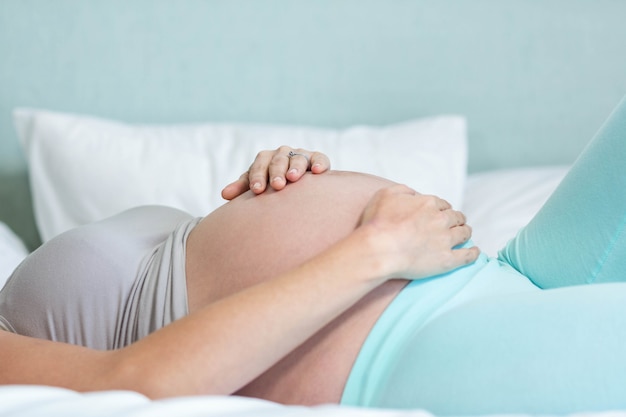 Pregnant woman lying on her bed in her bedroom