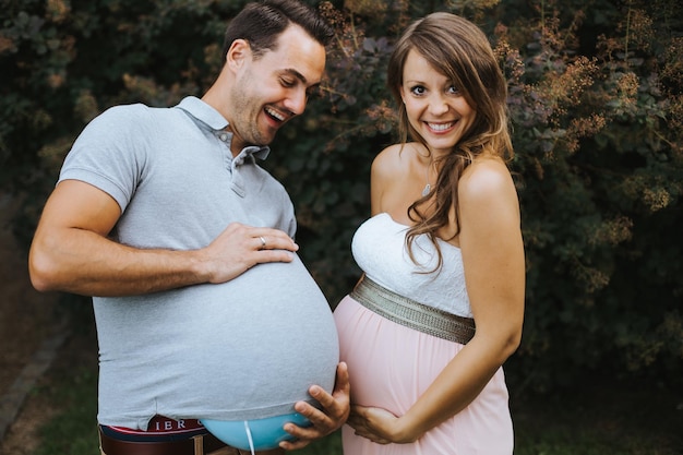 Photo pregnant woman making face while holding husband stomach