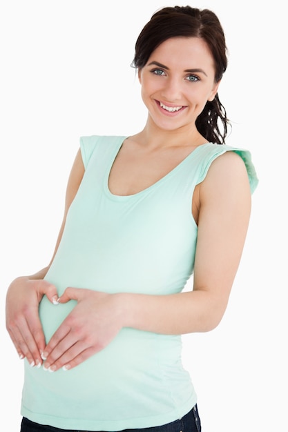 Pregnant woman making a heart with her hands on her belly