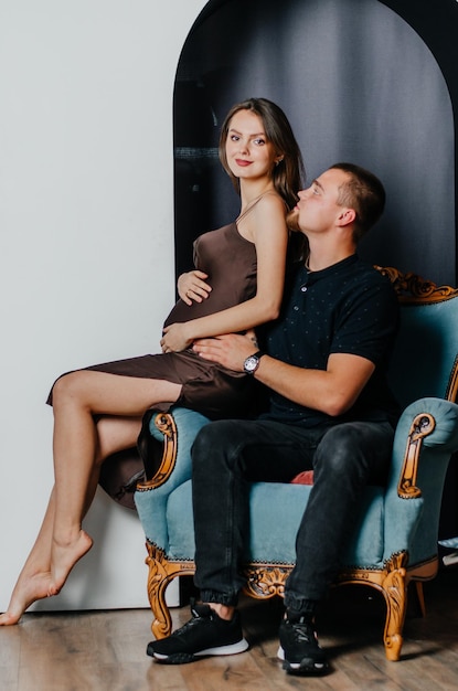 a pregnant woman and a man are sitting in a chair