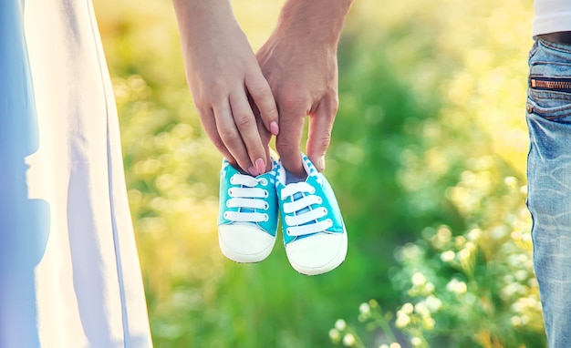 Pregnant woman and man hold baby shoes