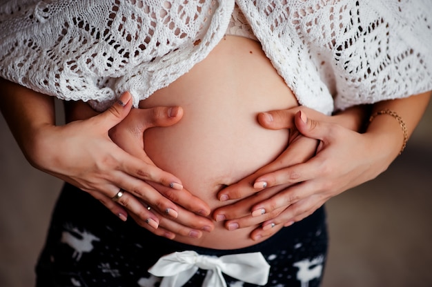 Una donna incinta e un uomo che tiene il suo stomaco. il concetto di aspettare la nascita di un bambino.