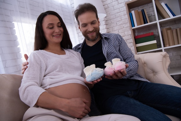 Pregnant Woman and Man is Holding Shoes for Baby