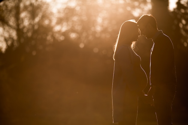 妊娠中の女性と秋の公園でポーズを取っている男