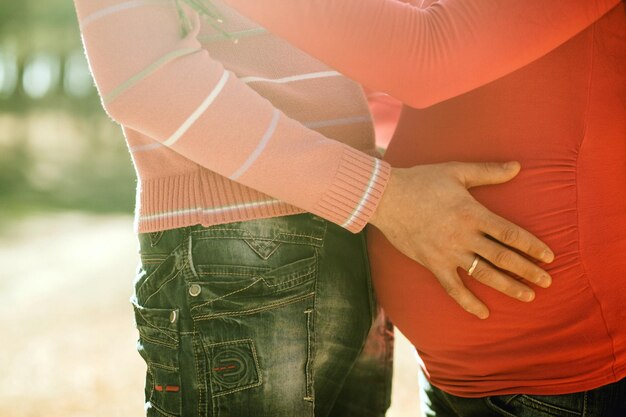 妊娠中の女性と男性は屋外でリラックスします秋の前の妊娠中のカップル