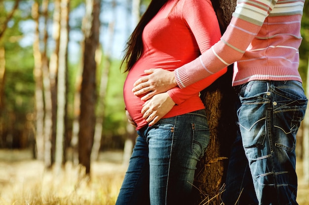 Pregnant woman and man relax outdoors Pregnant couple in autumn fores