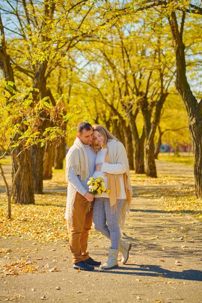 Pregnant woman and man at sunny warm autumn park