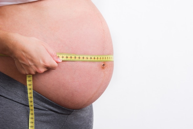 Pregnant woman measuring her belly