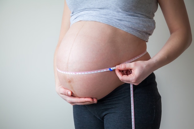 Pregnant woman measuring her belly