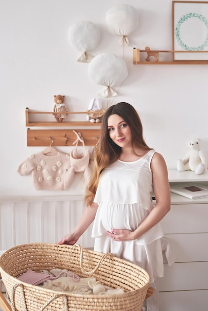 Photo pregnant woman in nursery preparation for childbirth babies wear and accessories