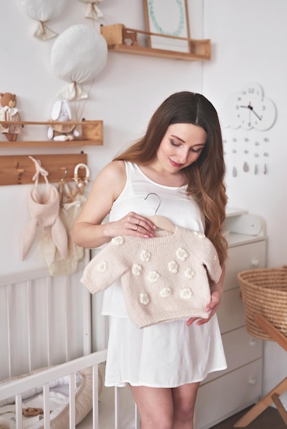 Pregnant woman in nursery Preparation for childbirth Babies wear and accessories