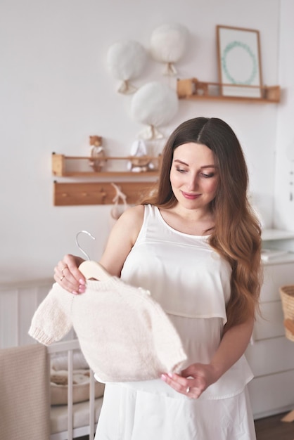 Photo pregnant woman in nursery preparation for childbirth babies wear and accessories