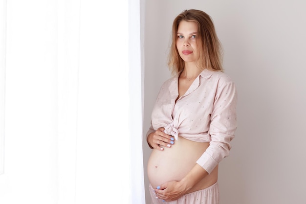 Donna incinta in pigiama alla finestra