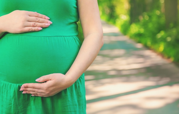 Pregnant woman in the park on the background of the road.