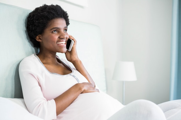 Pregnant woman on the phone on bed 