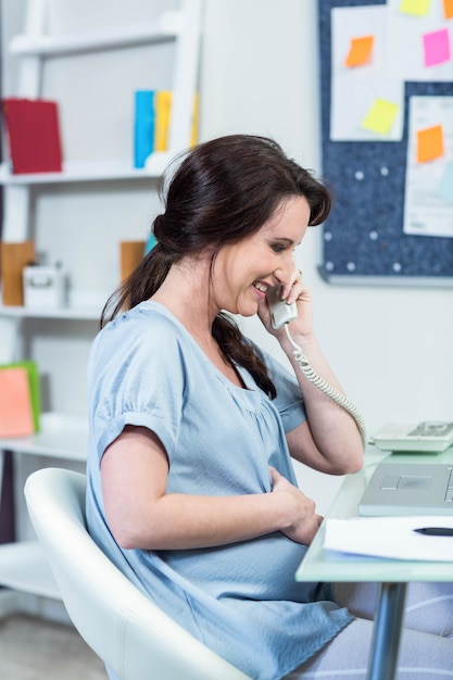 Pregnant woman on the phone at desk 