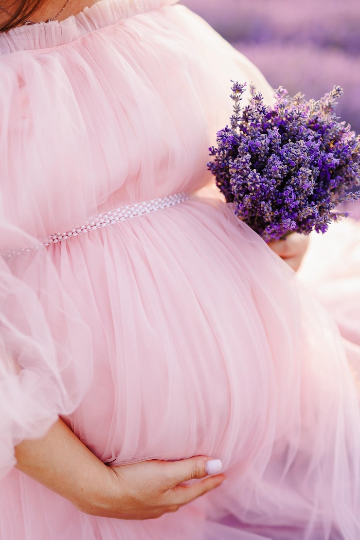 Photo a pregnant woman in pink dress the concept of expecting a babybaby girlclose uplavender flowers