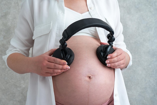 Pregnant woman playing music to her baby through headphones putting them on her belly