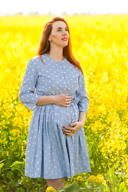 Pregnant woman portrait on the yellow field