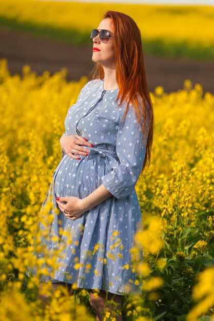 Pregnant woman portrait on the yellow field