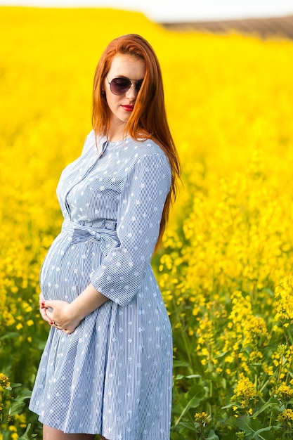 Pregnant woman portrait on the yellow field